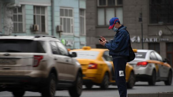 Мужчина в защитной маске вызывает такси наа Тверской улице во время режима самоизоляции жителей в Москве
