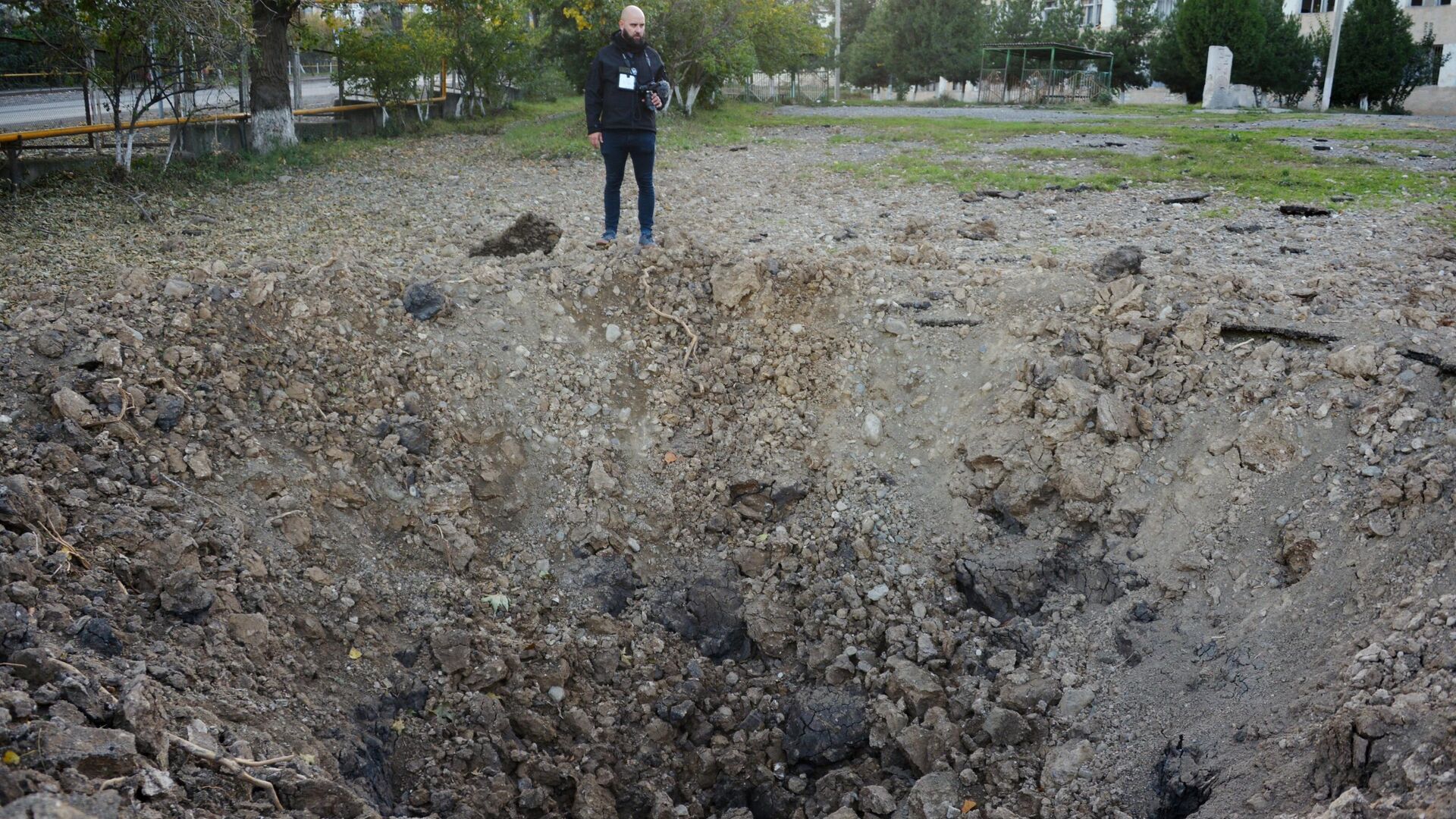 Мужчина возле воронки от упавшего снаряда возле здания школы №10 в Степанакерте Мужчина возле воронки от упавшего снаряда возле здания школы №10 в Степанакерте - РИА Новости, 1920, 17.10.2020