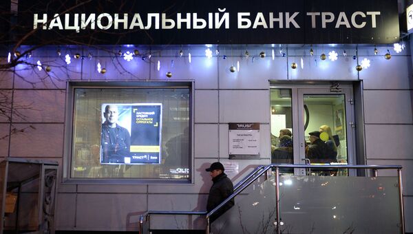 Клиент выходит из офиса банка Траст в Москве. Архивное фото Клиент выходит из офиса банка Траст в Москве. Архивное фото