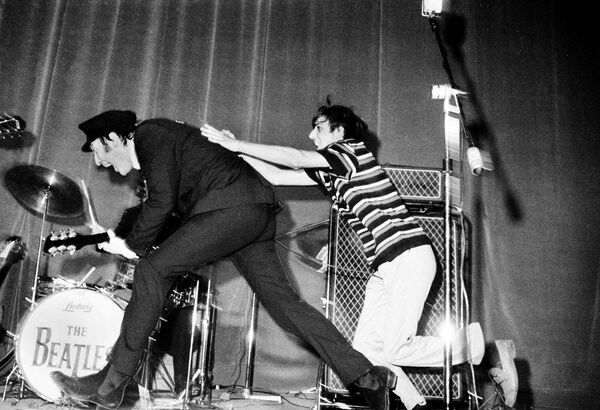 Джон Леннон уклоняется от фаната группы The Beatles во время выступления в Риме, 1965 год Джон Леннон уклоняется от фаната группы The Beatles во время выступления в Риме, 1965 год