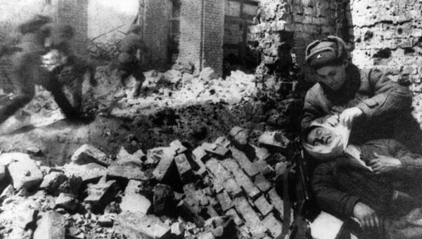 Медсестра перевязывает раненого солдата во время уличных боев в Сталинграде Медсестра перевязывает раненого солдата во время уличных боев в Сталинграде