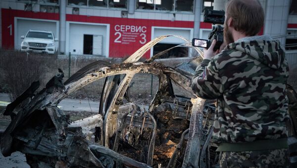 Мужчина снимает автомобиль, сгоревший после обстрела Донецка 4 февраля 2015. Архивное фото Мужчина снимает автомобиль, сгоревший после обстрела Донецка 4 февраля 2015. Архивное фото