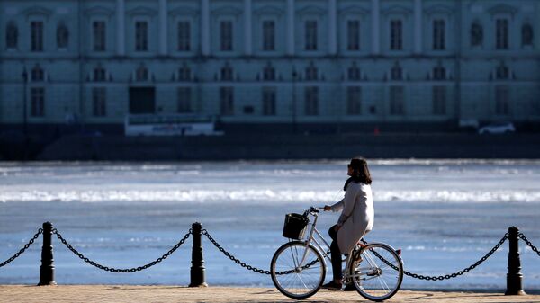 Девушка едет на велосипеде по Набережной Невы в Санкт-Петербурге Девушка едет на велосипеде по Набережной Невы в Санкт-Петербурге