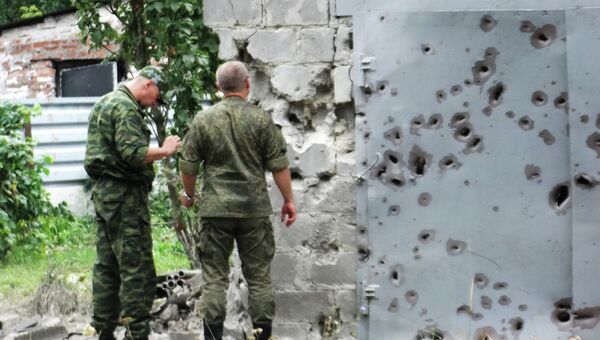 Сотрудники МЧС у ворот, поврежденных осколками в результате обстрела Донецка. Архивное фото Сотрудники МЧС у ворот, поврежденных осколками в результате обстрела Донецка. Архивное фото