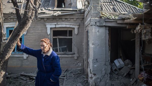 Женщина у поврежденного в результате обстрела дома в поселке Александровка. Архивное фото Женщина у поврежденного в результате обстрела дома в поселке Александровка. Архивное фото