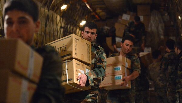 Сирийские военнослужащие разгружают коробки с гуманитарной помощью из России. Архивное фото Сирийские военнослужащие разгружают коробки с гуманитарной помощью из России. Архивное фото