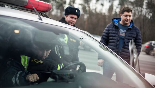 Сотрудник ГИБДД проверяет документы у водителя. Архивное фото Сотрудник ГИБДД проверяет документы у водителя. Архивное фото