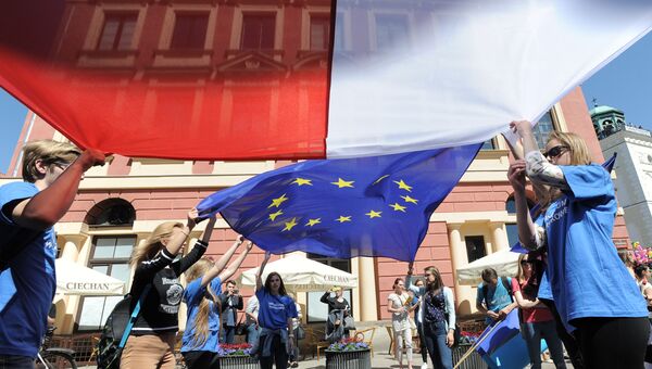 Молодые люди держат флаги Польши и Евросоюза. Архивное фото Молодые люди держат флаги Польши и Евросоюза. Архивное фото