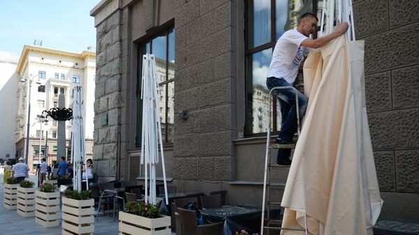 Рабочий устанавливает навес на летней веранде на реконструированной Тверской улице в Москве Рабочий устанавливает навес на летней веранде на реконструированной Тверской улице в Москве
