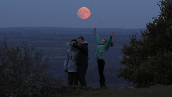 Семья фотографируется на фоне луны, Лафборо, Великобритания. 13 ноября 2016 Семья фотографируется на фоне луны, Лафборо, Великобритания. 13 ноября 2016