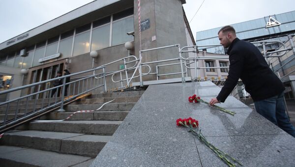 Мужчина возлагает цветы у входа в вестибюль станции метро Сенная площадь в Санкт-Петербурге Мужчина возлагает цветы у входа в вестибюль станции метро Сенная площадь в Санкт-Петербурге