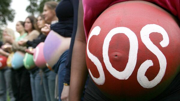 Беременная женщина с надписью SOS на животе на митинге в Лондоне Беременная женщина с надписью SOS на животе на митинге в Лондоне