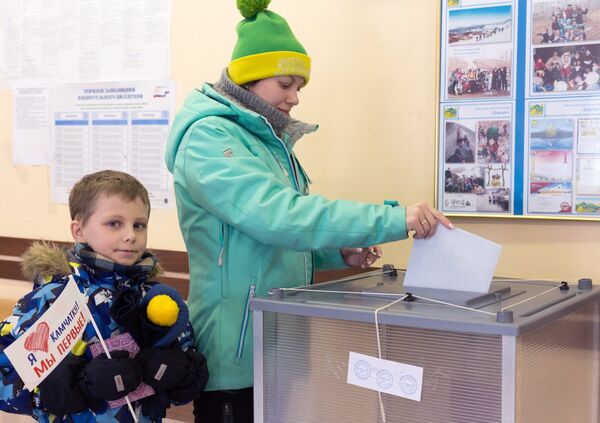 Женщина опускает бюллетень в урну на выборах президента РФ на избирательном участке №51 в Петропавловске-Камчатском. Женщина опускает бюллетень в урну на выборах президента РФ на избирательном участке №51 в Петропавловске-Камчатском.
