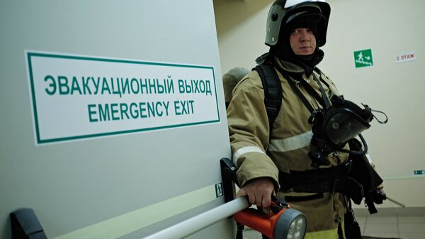 Сотрудник противопожарной службы у эвакуационного выхода. Архивное фото Сотрудник противопожарной службы у эвакуационного выхода. Архивное фото