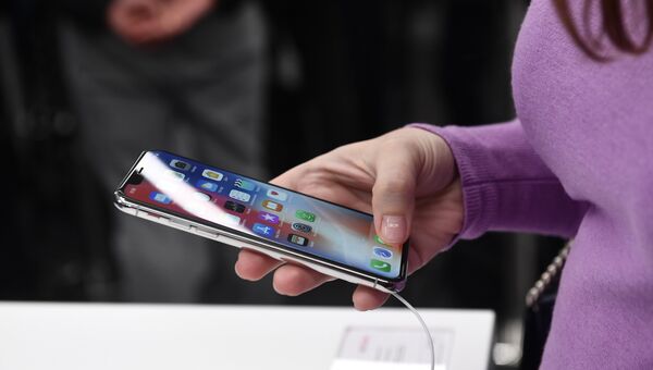 Покупательница рассматривает новый смартфон iPhone X. Архивное фото Покупательница рассматривает новый смартфон iPhone X. Архивное фото