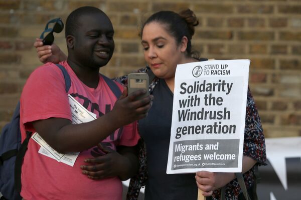 Участники с плакатми во время акции солидарности с поколением Windrush в Брикстоне, Лондон. 20 апреля 2018 Участники с плакатми во время акции солидарности с поколением Windrush в Брикстоне, Лондон. 20 апреля 2018