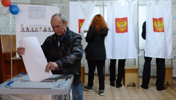 Мужчина опускает бюллетень во время голосования на выборах президента России на избирательном участке в Крыму Мужчина опускает бюллетень во время голосования на выборах президента России на избирательном участке в Крыму