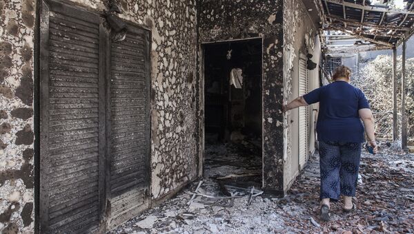 Женщина у своего дома, пострадавшего в результате лесных пожаров, в поселении Мати в Греции. 25 июля 2018 Женщина у своего дома, пострадавшего в результате лесных пожаров, в поселении Мати в Греции. 25 июля 2018