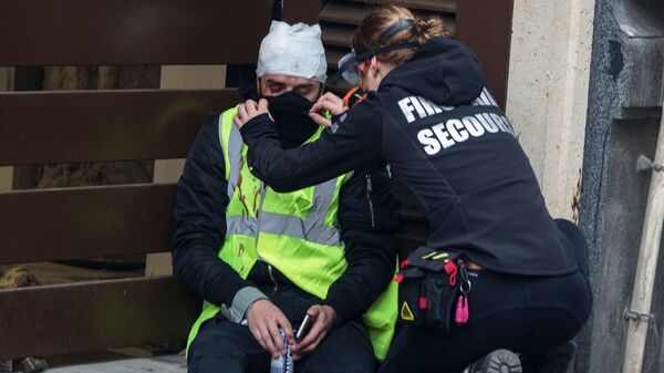 Участник акции протеста движения автомобилистов желтые жилеты в районе Триумфальной арки в Париже получает медицинскую помощь Участник акции протеста движения автомобилистов желтые жилеты в районе Триумфальной арки в Париже получает медицинскую помощь