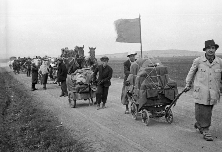Беженцы везут по дороге тележки со скарбом. В районе Вены. 1945 год Беженцы везут по дороге тележки со скарбом. В районе Вены. 1945 год