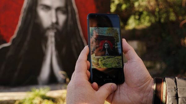 Мужчина фотографирует на смартфон граффити с изображением рэп-исполнителя Децла в Сочи Мужчина фотографирует на смартфон граффити с изображением рэп-исполнителя Децла в Сочи
