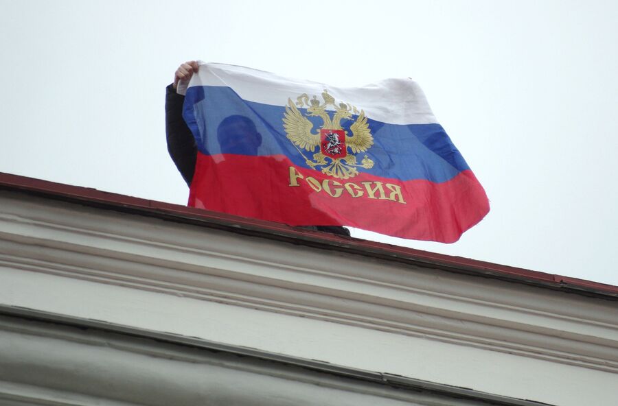 Местный житель с российским флагом на крыше Горсовета в Севастополе Местный житель с российским флагом на крыше Горсовета в Севастополе