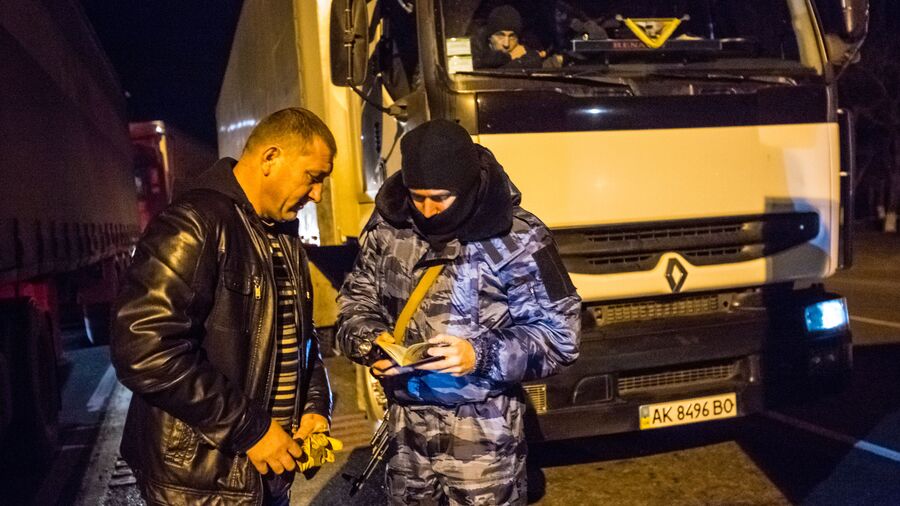Сотрудник подразделения милиции специального назначения Беркут проверяет документы на блокпосту на въезде в Крым в районе Армянска Сотрудник подразделения милиции специального назначения Беркут проверяет документы на блокпосту на въезде в Крым в районе Армянска