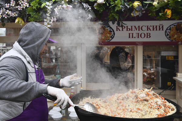 Повар раскладывает плов во время фестиваля Крымская весна в Москве Повар раскладывает плов во время фестиваля Крымская весна в Москве