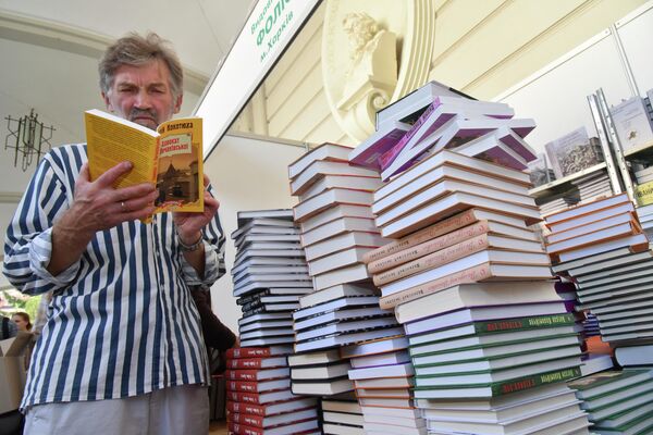 Посетитель читает книгу на книжной ярмарке во Львове Посетитель читает книгу на книжной ярмарке во Львове