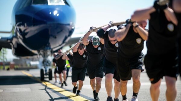 Мужчины тянут самолет JetBlue A320 во время ежегодных соревнований Plane Pull в Международном аэропорту Джона Ф. Кеннеди Мужчины тянут самолет JetBlue A320 во время ежегодных соревнований Plane Pull в Международном аэропорту Джона Ф. Кеннеди