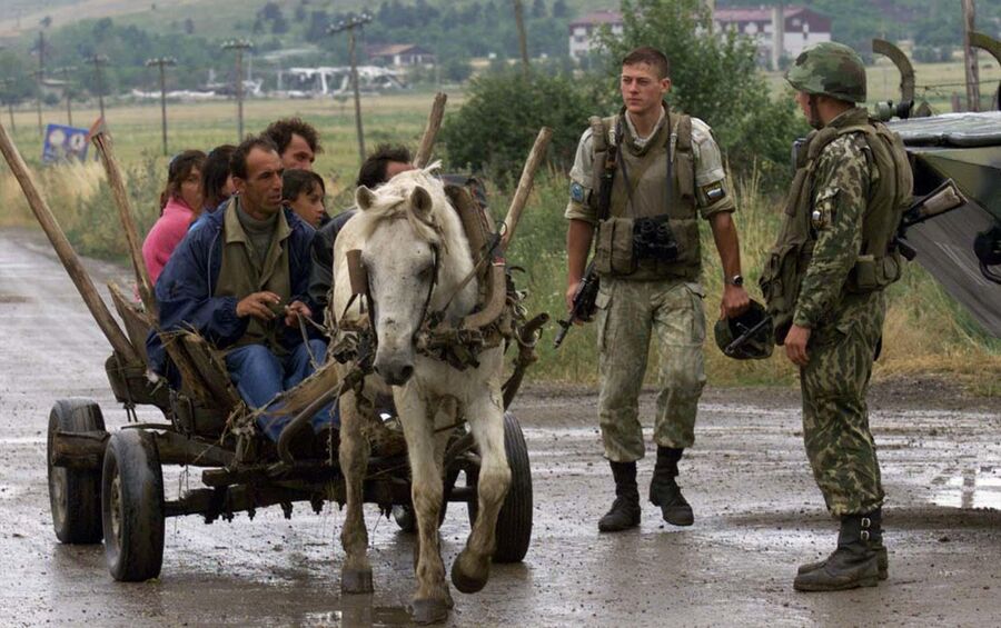Этнические албанцы проезжают мимо российских военных, дислоцированных у аэропорта Слатина в Приштине Этнические албанцы проезжают мимо российских военных, дислоцированных у аэропорта Слатина в Приштине