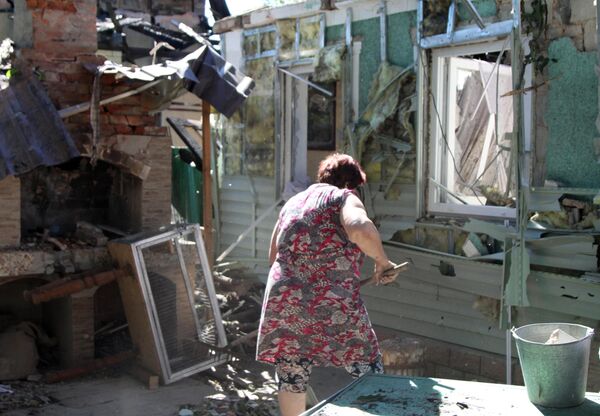 Женщина убирает мусор во дворе жилого дома в Донецке, пострадавшего в результате обстрела Женщина убирает мусор во дворе жилого дома в Донецке, пострадавшего в результате обстрела