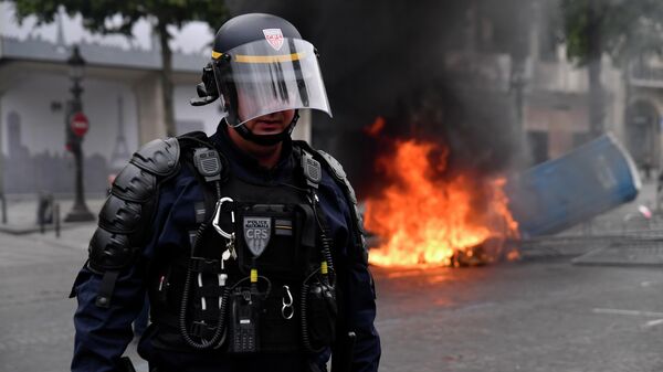 Сотрудник полиции во время беспорядков на Елисейских полях в Париже Сотрудник полиции во время беспорядков на Елисейских полях в Париже