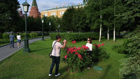 Молодой человек фотографирует девушку в Александровском саду в Москве Молодой человек фотографирует девушку в Александровском саду в Москве
