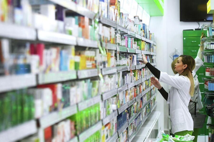 Фармацевт раскладывает лекарственные препараты в аптеке Фармацевт раскладывает лекарственные препараты в аптеке