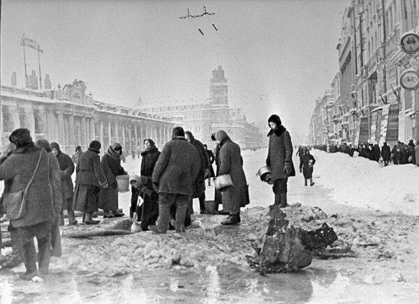 Жители блокадного Ленинграда набирают воду, появившуюся после артобстрела в пробоинах в асфальте Жители блокадного Ленинграда набирают воду, появившуюся после артобстрела в пробоинах в асфальте