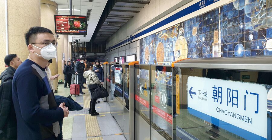 Пассажиры в защитных масках на одной из станций метро в Пекине