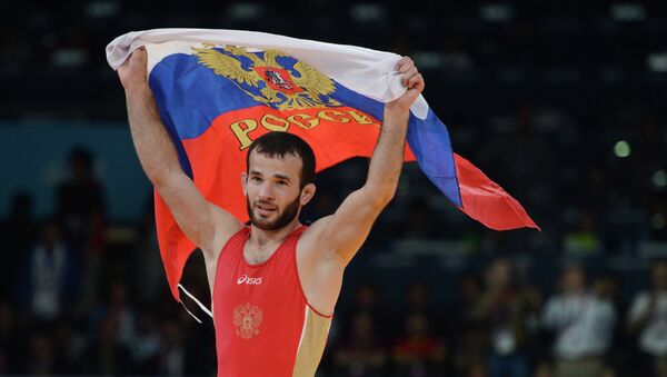 Российский борец Джамал Отарсултанов, завоевавший золотую медаль, с российским флагом после победы в финальном поединке Российский борец Джамал Отарсултанов, завоевавший золотую медаль, с российским флагом после победы в финальном поединке
