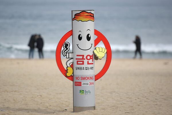 Знак о запрете курения на пляже Gyeongpo Beach в городе Каннын, Республика Корея Знак о запрете курения на пляже Gyeongpo Beach в городе Каннын, Республика Корея